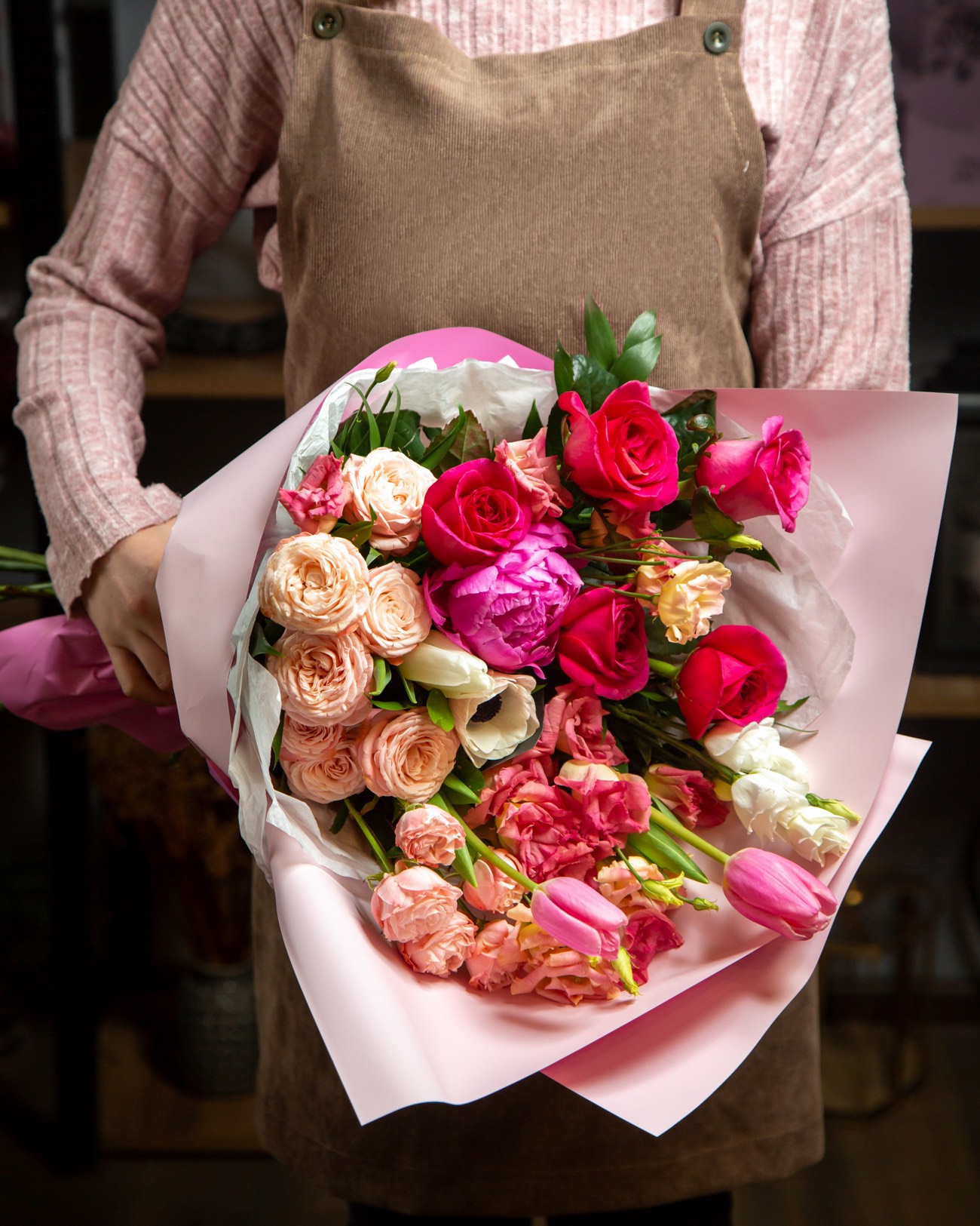 Florista sosteniendo un ramo de rosas, peonías y tulipanes